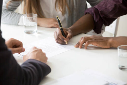 People signing closing documents at a table, symbolizing the final step before moving with MyTee Movers.