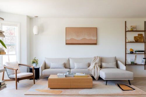 Modern, minimalist living room with soft natural light, neutral furniture, and a warm, welcoming “new home” feel.